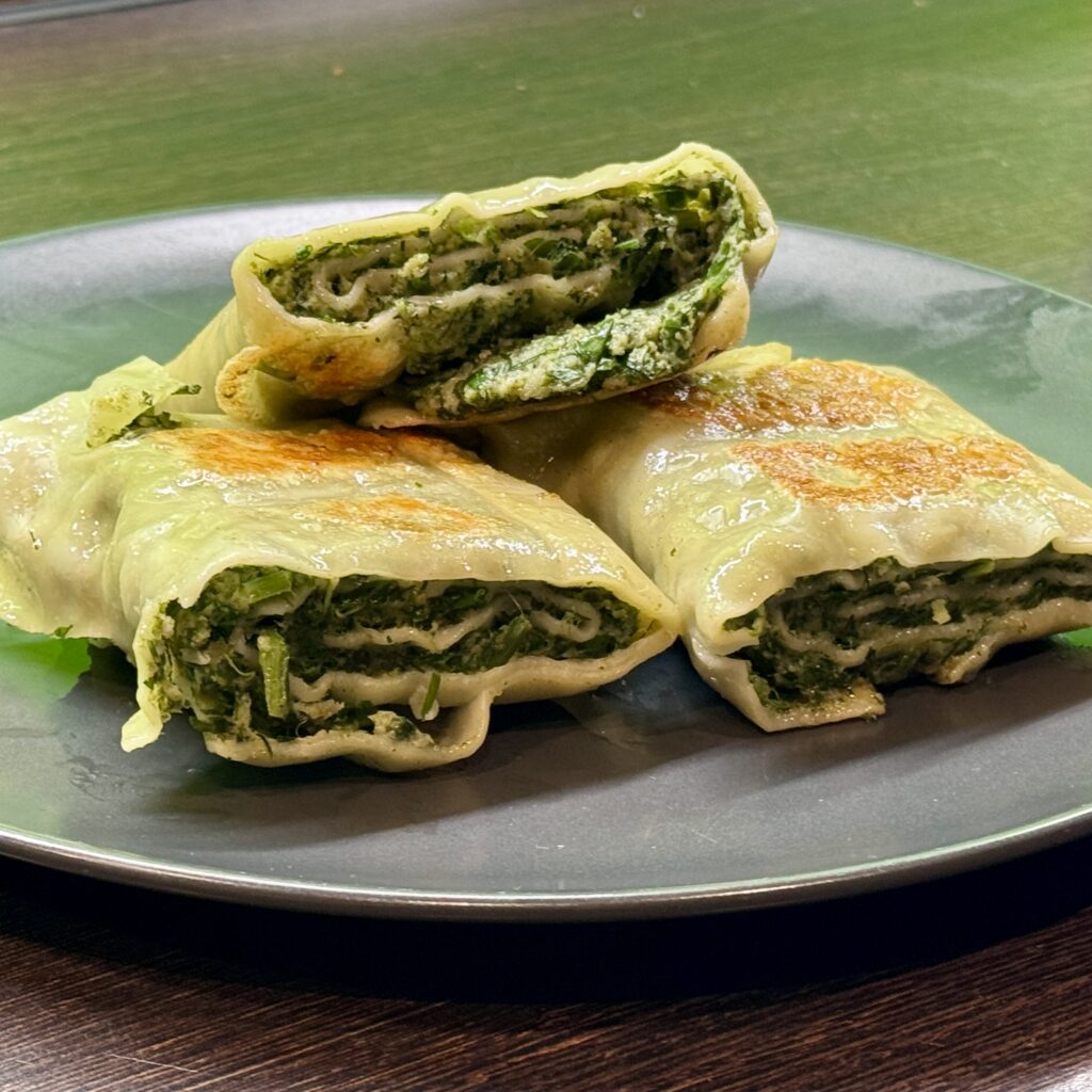 Drei goldbraun gebratene Maultaschen auf einem Teller, gefüllt mit einer würzigen Mischung aus Spinat und weiteren Zutaten.